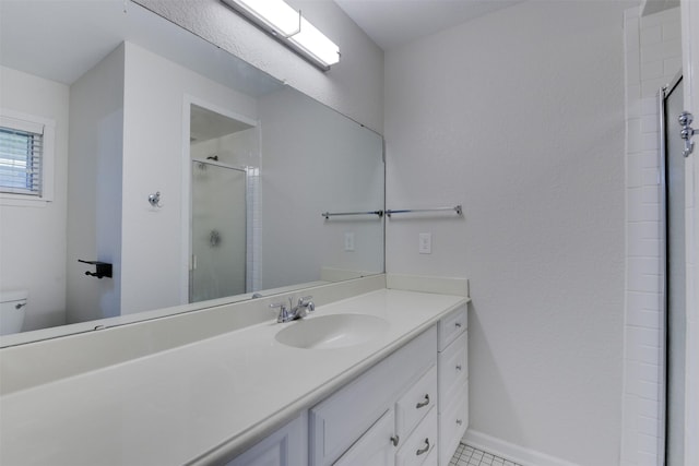 bathroom with vanity, baseboards, a stall shower, and toilet