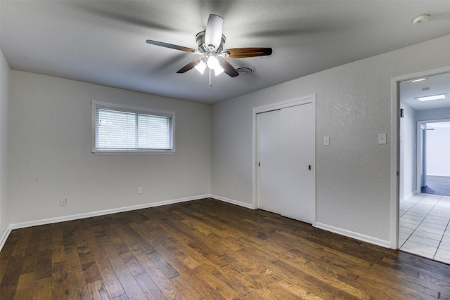 unfurnished bedroom with a ceiling fan, baseboards, visible vents, and hardwood / wood-style flooring