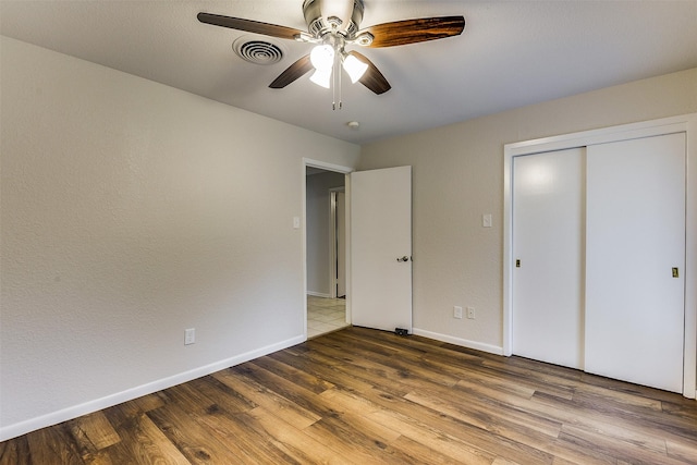 unfurnished bedroom with ceiling fan, baseboards, wood finished floors, visible vents, and a closet