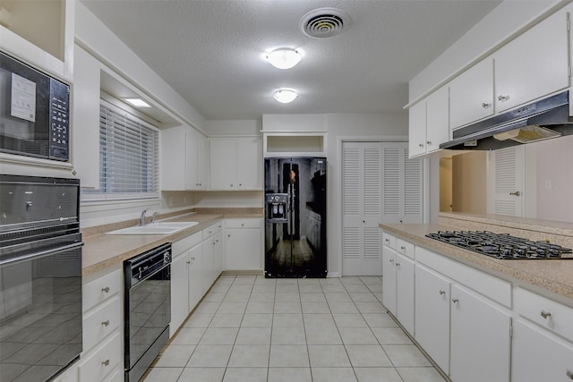 kitchen featuring visible vents, light countertops, under cabinet range hood, and black appliances