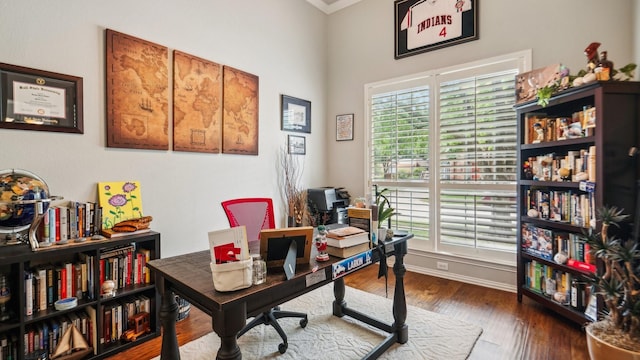 office with baseboards, a high ceiling, crown molding, and wood finished floors