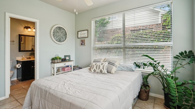 bedroom with light tile patterned flooring, baseboards, and ensuite bath