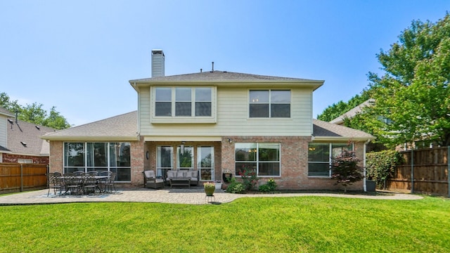 back of house featuring a fenced backyard, a chimney, a lawn, and a patio area