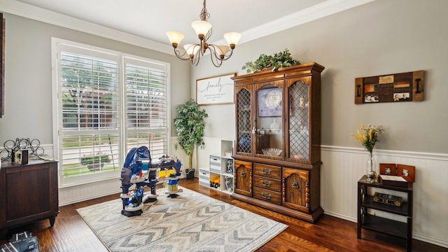 sitting room featuring an inviting chandelier, ornamental molding, dark wood-type flooring, and a wainscoted wall