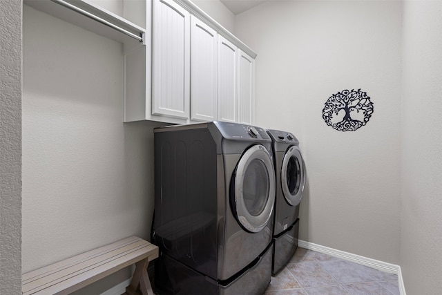 laundry room with light tile patterned floors, separate washer and dryer, baseboards, and cabinet space