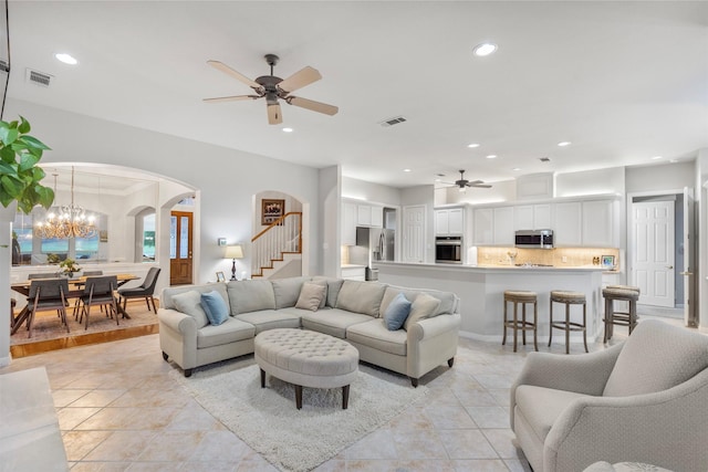 living area with visible vents, arched walkways, and ceiling fan with notable chandelier