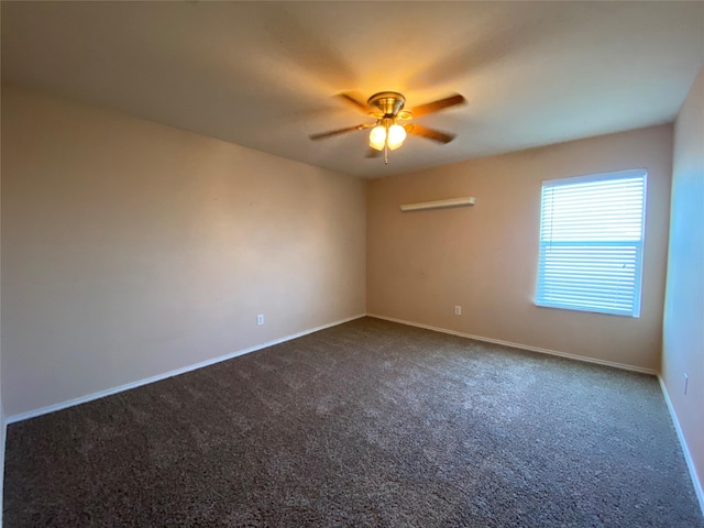 spare room with ceiling fan, baseboards, and dark colored carpet