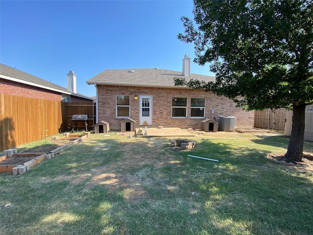 back of house with brick siding, a yard, a vegetable garden, and cooling unit