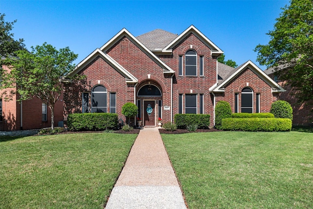 traditional-style home featuring brick siding and a front lawn