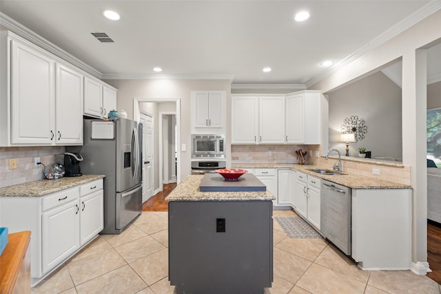 kitchen featuring appliances with stainless steel finishes, a sink, decorative backsplash, a kitchen island, and visible vents