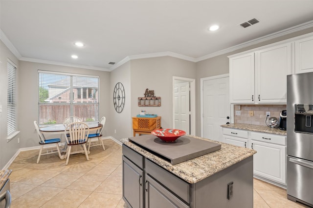 kitchen featuring a kitchen island, stainless steel refrigerator with ice dispenser, visible vents, crown molding, and light tile patterned floors