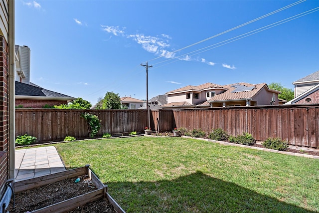 view of yard with a residential view, a fenced backyard, and a vegetable garden