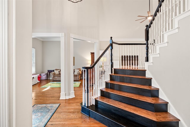 staircase with wood finished floors and a towering ceiling
