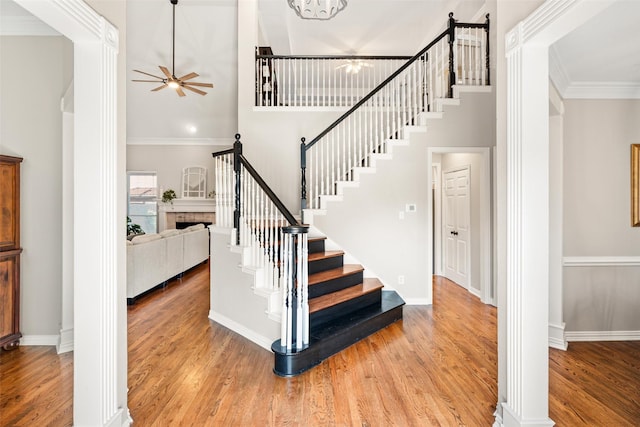 6017 Madera Ct, Plano, TX 75024 - staircase featuring ceiling fan, a high ceiling, wood finished floors, a fireplace, and decorative columns