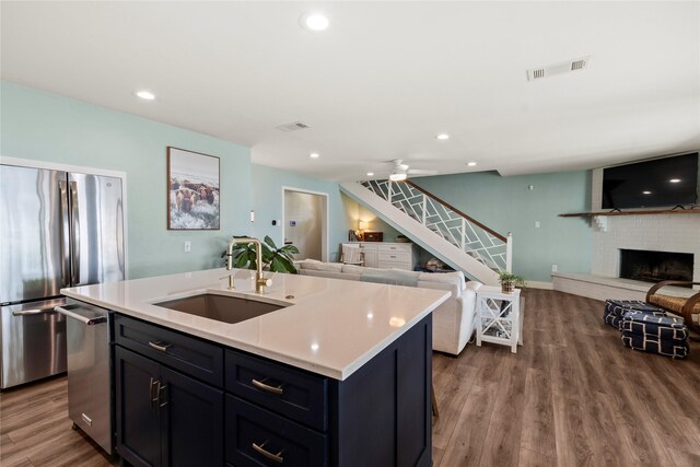 kitchen featuring visible vents, open floor plan, light countertops, a sink, and appliances with stainless steel finishes