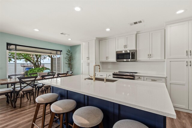 kitchen featuring visible vents, appliances with stainless steel finishes, a sink, light wood finished floors, and recessed lighting