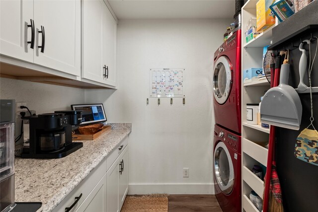 laundry area featuring baseboards, wood finished floors, and stacked washer / dryer