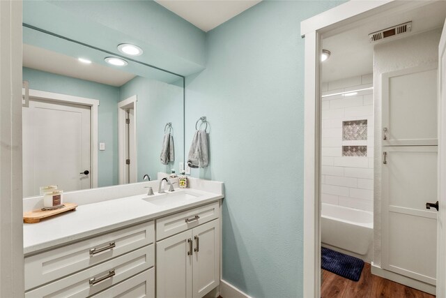 bathroom featuring shower / tub combination, vanity, recessed lighting, wood finished floors, and visible vents