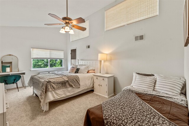 bedroom with ceiling fan, visible vents, baseboards, a high ceiling, and light carpet
