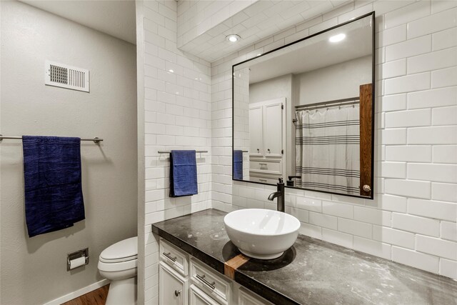 full bathroom featuring visible vents, decorative backsplash, vanity, wood finished floors, and toilet