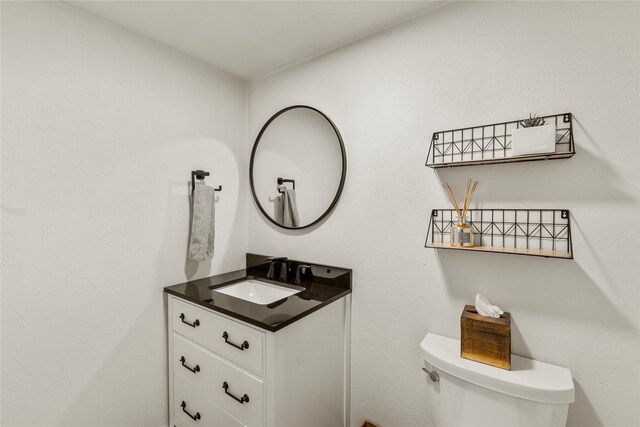 half bath featuring vanity and toilet