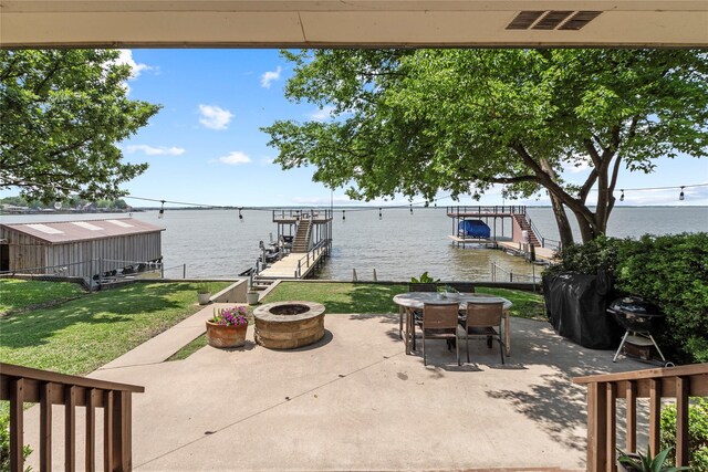 view of patio featuring a water view, a dock, outdoor dining area, and an outdoor fire pit