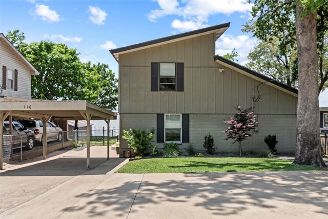 view of front of house featuring fence, concrete driveway, a front lawn, and brick siding