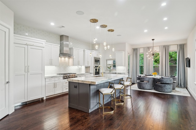 kitchen with backsplash, appliances with stainless steel finishes, white cabinets, dark wood-style floors, and wall chimney exhaust hood