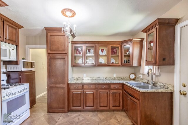 kitchen with a sink, glass insert cabinets, brown cabinetry, and white appliances