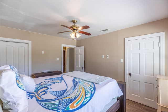 bedroom with a ceiling fan, visible vents, wood finished floors, and a closet