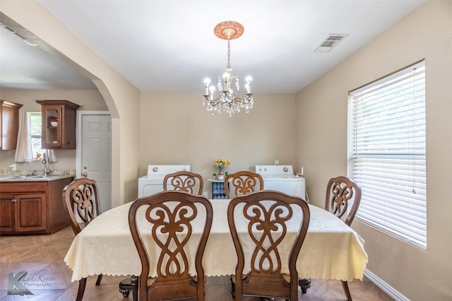 dining room with arched walkways, a notable chandelier, washer / dryer, and visible vents