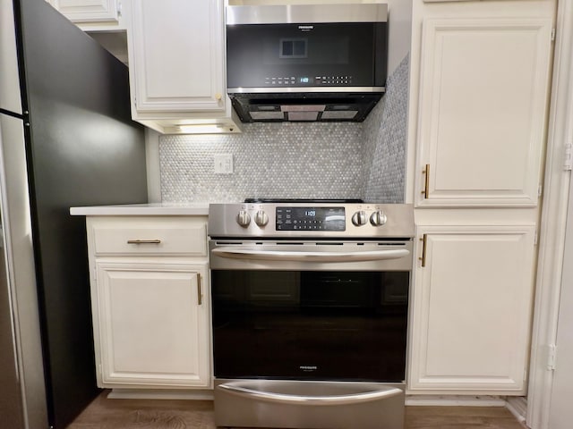 kitchen with tasteful backsplash, stainless steel appliances, wood finished floors, and white cabinetry