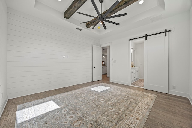 4771 Sasha Way, Caddo Mills, TX 75135 - unfurnished bedroom with visible vents, a barn door, a raised ceiling, and wood finished floors