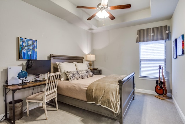 bedroom featuring a ceiling fan, a tray ceiling, baseboards, and carpet