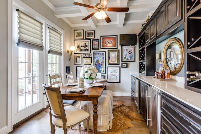 dining room with a ceiling fan, crown molding, a dry bar, beam ceiling, and coffered ceiling