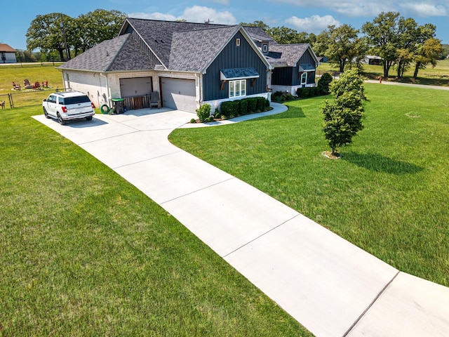 view of front of house with board and batten siding, an attached garage, concrete driveway, and a front lawn