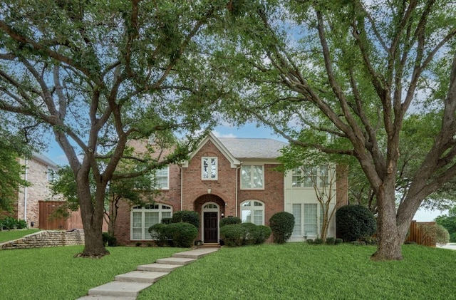 view of front of property featuring fence, brick siding, and a front yard