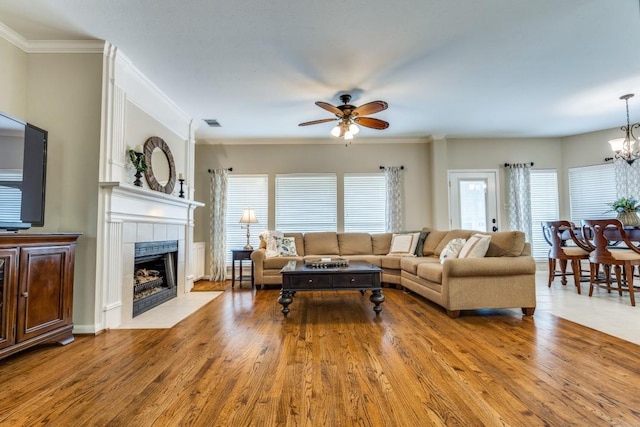 living area with visible vents, wood finished floors, ceiling fan with notable chandelier, and a tile fireplace