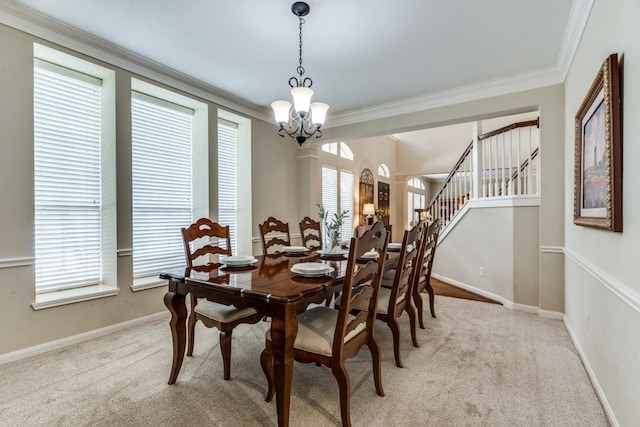 dining room featuring an inviting chandelier, baseboards, ornamental molding, and light colored carpet
