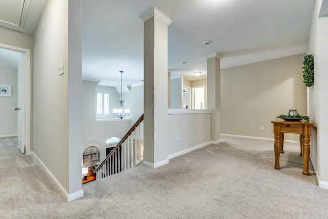 hall featuring carpet flooring, a notable chandelier, baseboards, and an upstairs landing