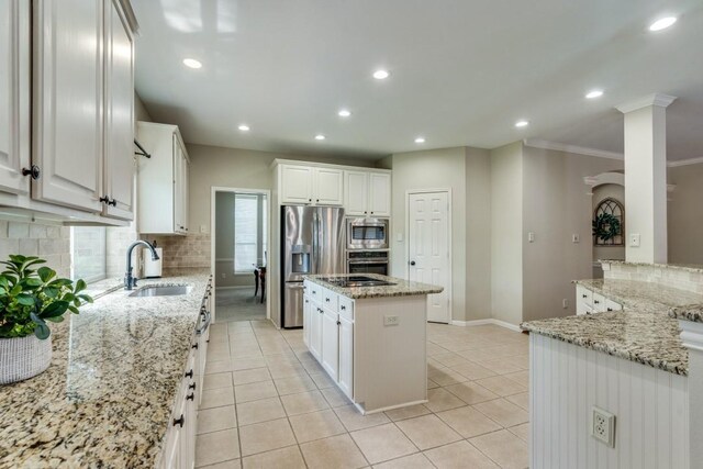 kitchen featuring a center island, recessed lighting, tasteful backsplash, a sink, and appliances with stainless steel finishes