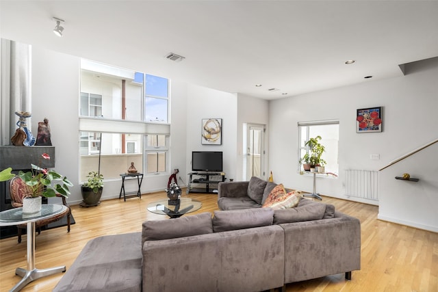 living room featuring radiator heating unit, recessed lighting, baseboards, light wood-type flooring, and visible vents