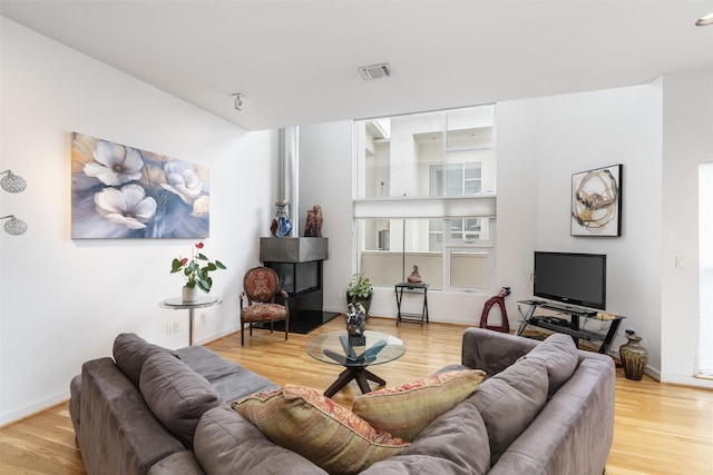 living room with light wood-style floors, baseboards, and visible vents