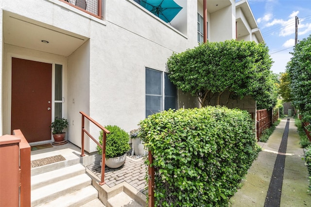 doorway to property with fence and stucco siding