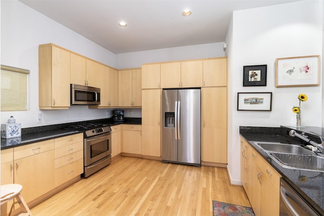 kitchen with stainless steel appliances, a sink, and light brown cabinets