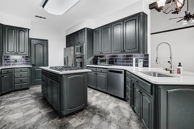 kitchen with a sink, light countertops, stainless steel appliances, a peninsula, and decorative backsplash