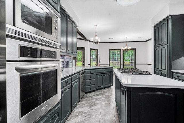 kitchen featuring appliances with stainless steel finishes, a sink, light countertops, a peninsula, and an inviting chandelier