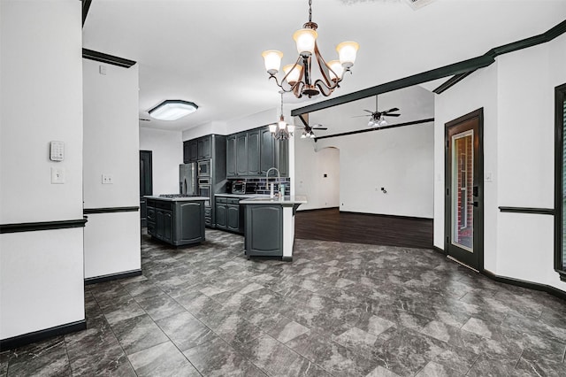 kitchen with baseboards, arched walkways, ceiling fan with notable chandelier, and a kitchen island