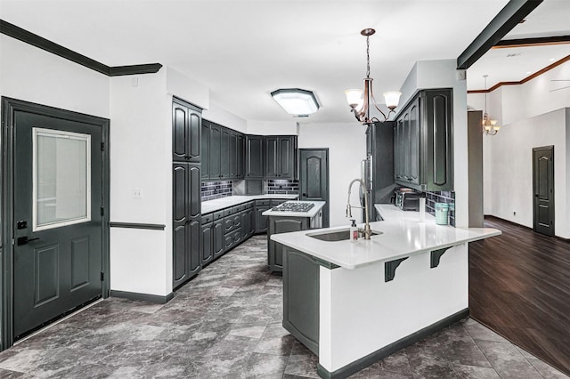 kitchen with a notable chandelier, a sink, light countertops, a breakfast bar area, and a peninsula
