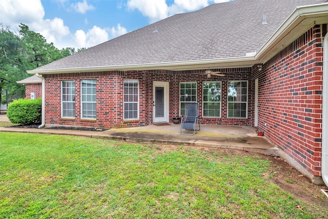 rear view of property featuring a lawn, brick siding, a patio area, and roof with shingles